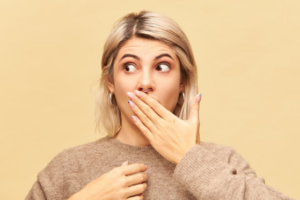 Woman worried about gum disease covering her mouth